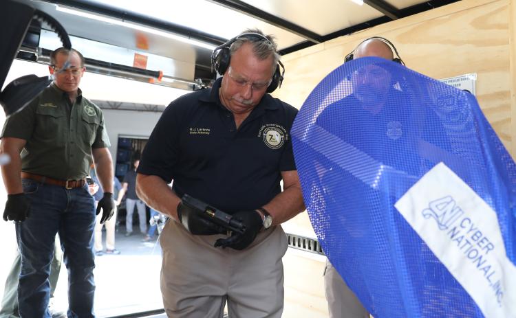 State Attorney R.J. Larizza, center, prepares to test fire a gun as investigators seek new leads on cases involving seized firearms. Photo courtesy of the Putnam County Sheriff's Office.