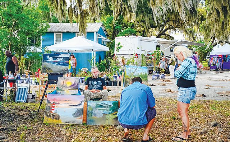 File photo. Two people look over a vendor's art as they determine whether to make a purchase at the Crescent City Art & Farmers Market last summer.