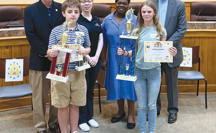 Spelling bee champion Jillian Huntley, front right, and runner-up Nicolas Penta, front left, hold their trophies and certificates after the 54th Annual Putnam County School District Spelling Bee on Wednesday. They are standing with the Flagg family, who provided the trophies, and Joe Pickens, the spelling bee moderator and president of St. Johns River State College.