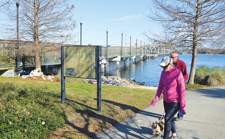 A couple walks their dog at the Palatka riverfront Friday next to the closed boardwalk that will soon be repaired and reopened.