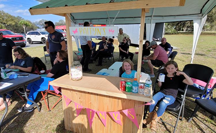 Eight-year-old Raegan Gill, right, and 7-year-old Paityn Wilkinson, seated beside her, work a lemonade stand Friday at the Putnam County Government Complex. The two girls were helping first responders with the Putnam County Fire Rescue Local 3529 firefighters union raise money for 5-year-old Nathan Scott. Nathan was severely injured in an accidental fire at his West Putnam home Christmas Eve.
