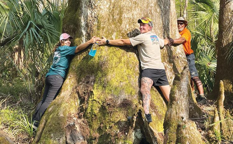 Military veterans, from left to right, Brandi Dziegiel, Austin Jenkins and Joe Howard hug a tree during their multi-day trek along the Ocala-to-Osceola Wildlife Corridor in February.