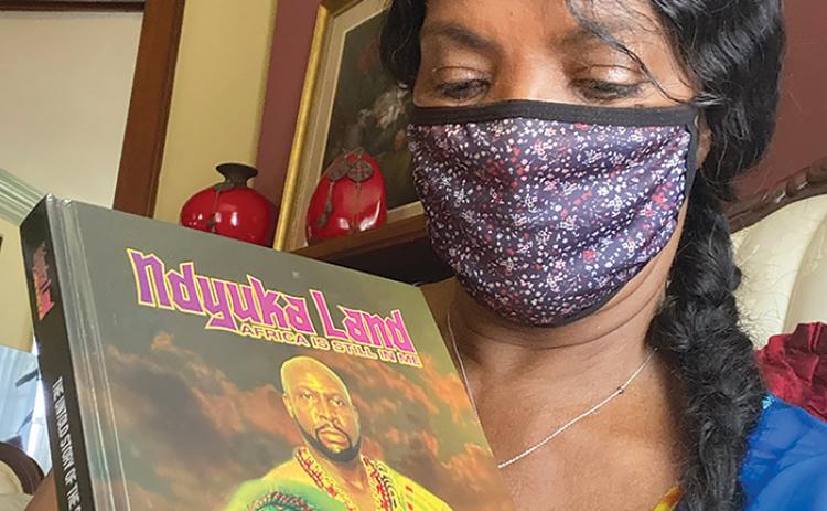 Angel Duke holds a copy of “Ndyuka Land: Africa is Still in Me” by Daniel Domini, who will be in Crescent City on Saturday.