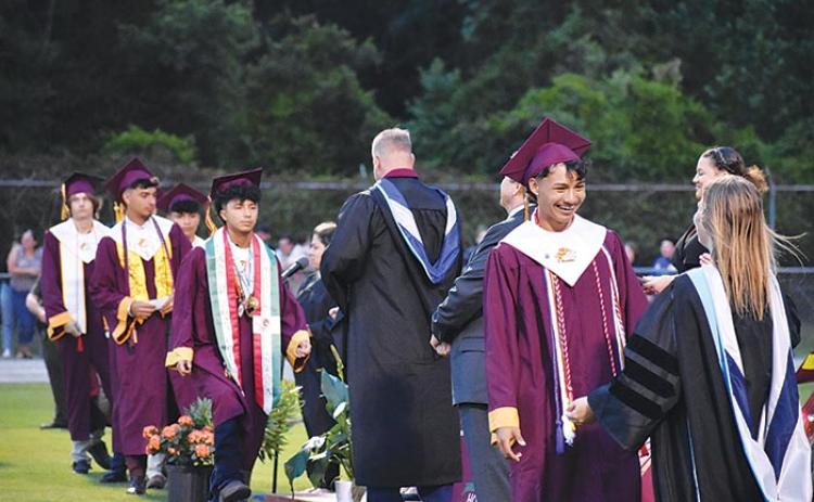 A Crescent City Junior-Senior High School graduate prepares to hug one of the school's administrators after receiving his diploma at the commencement ceremony.