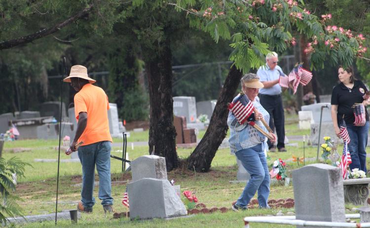 Cemetary caretaker Anthony Flowers, left, Interlachen Town Councilwoman Joni Connors, center in foreground, Town Office Manager Angie Glisson, right, and county Republican Executive Committee Chair Tom Williams, at back, seek out the grave markers of military service members Monday in Interlachen at Pineview Cemetery. The volunteers donated their time to make sure that veterans were remembered in advance of the Memorial Day holiday. (CASMIRA HARRISON/Palatka Daily News)