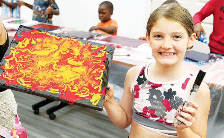 Hazel Martin, 11, shows off her finished projects during last week’s painting class.