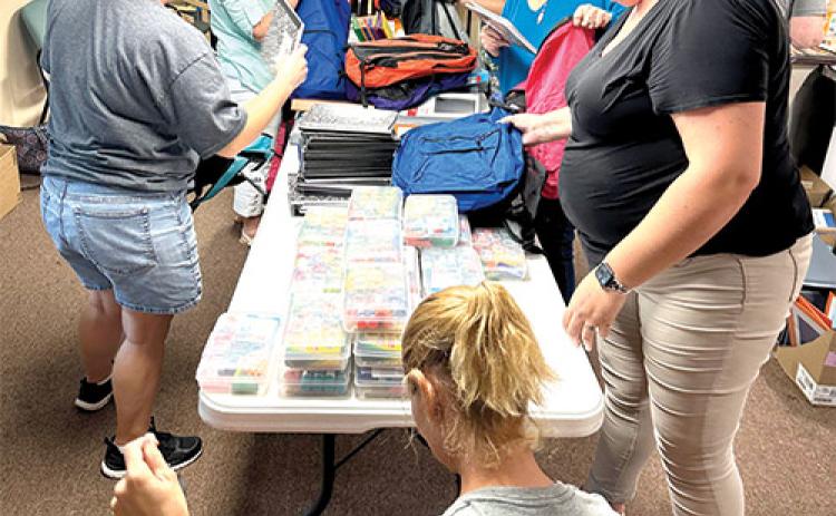 Photo submitted by Stephanie Anderson -- New Grace Baptist Woman’s Ministry and youth pack backpacks Wednesday evening with school supplies that will be given away Saturday at the Interlachen Soup Kitchen from 10 a.m. – 1 p.m.
