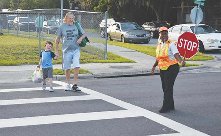 BRANDON D. OLIVER/Palatka Daily News -- A crossing guard helps two people safely get across the street to Moseley Elementary School in Palatka on the first day of school.
