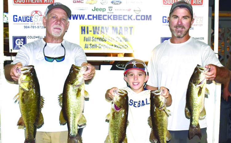 From left, Brett Bollinger, Justin Atkinson,Jr., and Justin Atkinson hold up their winning fish from last Thursday’s Corky Bell Evening Bass Tournament. (GREG WALKER / Daily News correspondent)