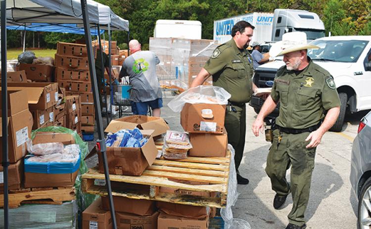 BRANDON D. OLIVER/Palatka Daily News -- Putnam County Sheriff's Office deputies distribute food to people's cars during Epic-Cure's giveaway Wednesday.