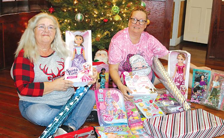 TRISHA MURPHY/Palatka Daily News – Martha Mann, left, and Linda Frank, sit in front of a Christmas tree where they are placing donated toys for needy children for Christmas through the “Angels Amongst Us” toy drive.