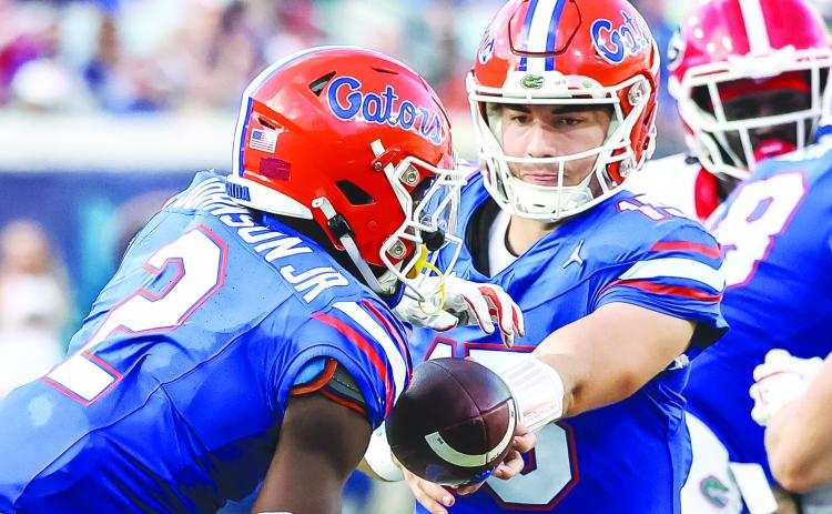 Florida quarterback Graham Mertz hands the ball off to running back Montrell Johnson Jr. during the Gators’ 43-20 loss to Georgia on Saturday. (JOHN STUDWELL / Special to the Daily News)
