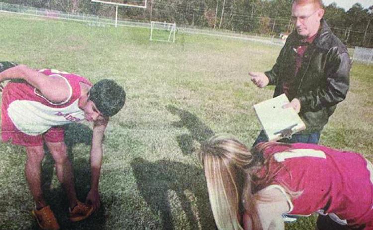 Crescent City Junior-Senior High School cross country coach Phil Johnson goes over technique with his top boys runner, Enrique Benitez, and top girls runner, Kristen Boyd, during a 2005 practice at the school. Johnson, who died on Dec. 18, was the Raiders’ first coach in the sport from 1998-2005 and retired winning the Daily News’ Coach of the Fall honor in 2005. (MARK BLUMENTHAL / Palatka Daily News)