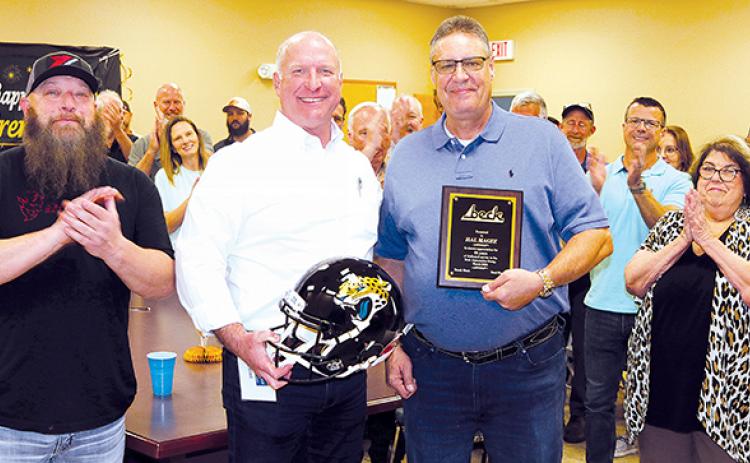 TRISHA MURPHY/Palatka Daily News – Beck Automotive Group President and CEO Breck Sloan, left, holds a Jacksonville Jaguars helmet signed by former player Fred Taylor that was presented to Hal Magee, right, Friday at Magee’s retirement celebration.