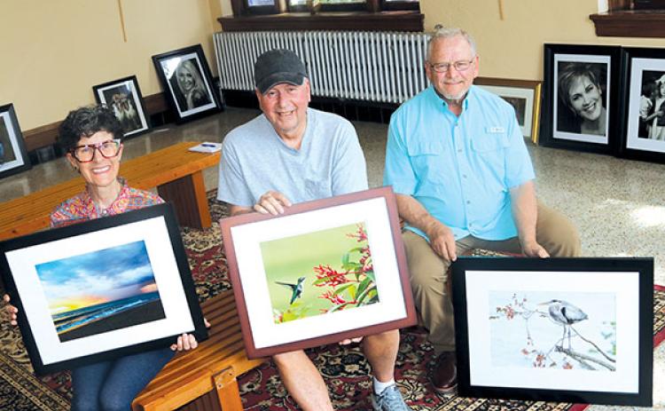 TRISHA MURPHY/Palatka Daily News – From left, Hollis Bliss, Jim Bailey and Tom Deputy hold framed copies of their photographs that will be featured in the “Through the Artists Lens” photo exhibit that launches Friday.